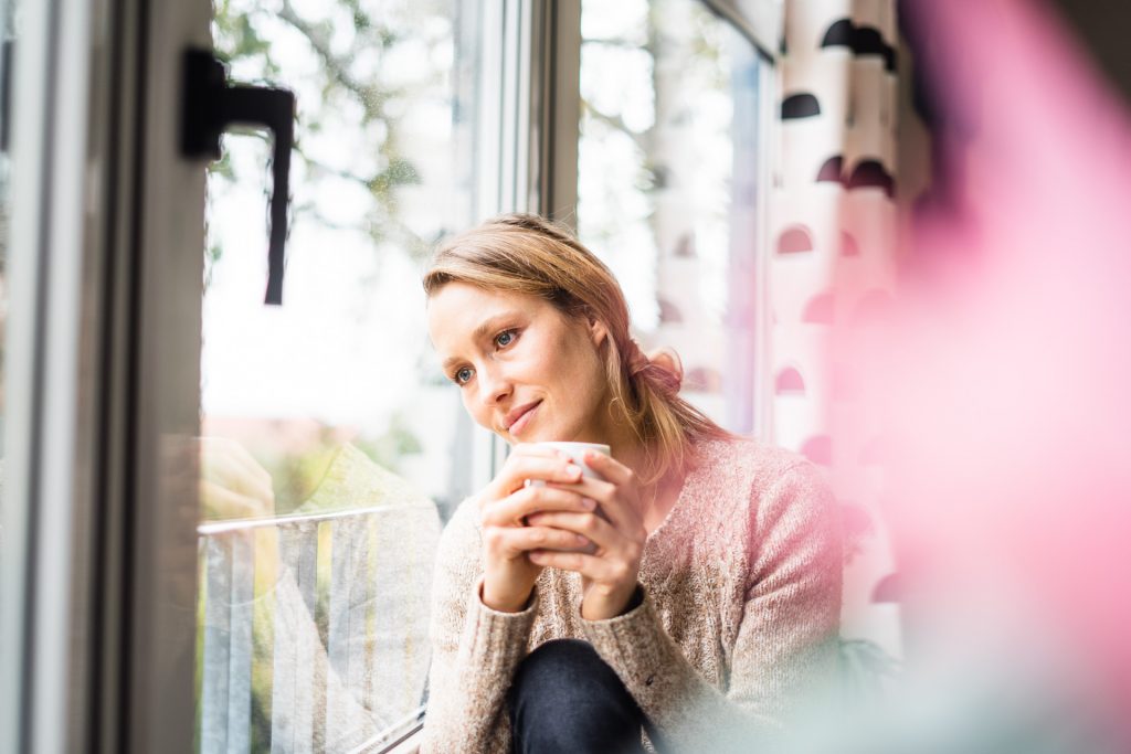 Cozy Winter Stimmung Frau schaut aus Fenster