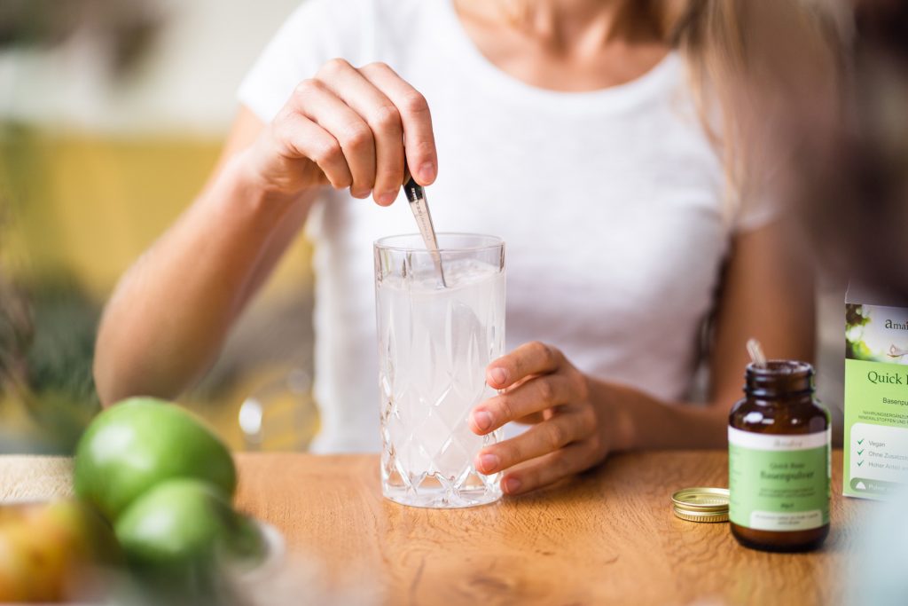 Pulver umrühren im Glas Frau sitzt am Tisch bei Produktshooting München Food Startup
