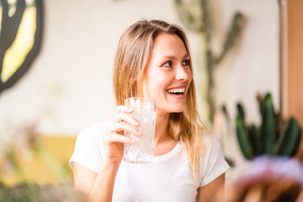 Model lacht bei Produkt Shooting mit Glas in Hand München