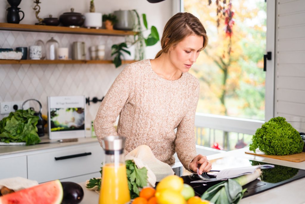 Frau steht in Küche München Modern blättert in Buch