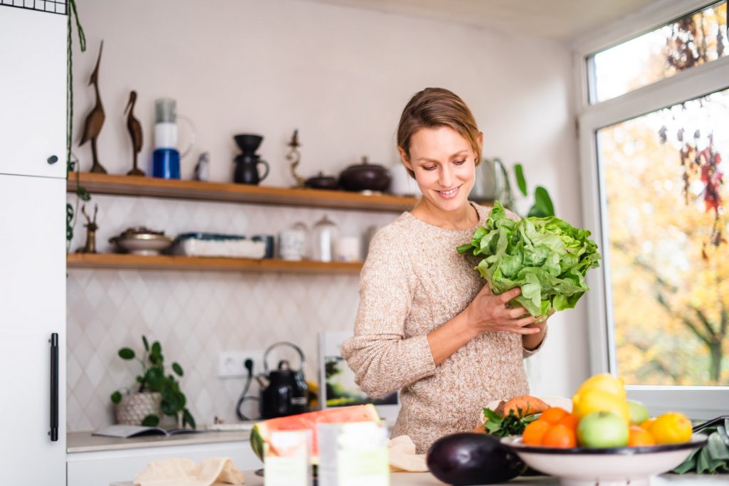 Frau steht in moderner Küche mit Salat in Hand bei Produkt Foto Shooting München