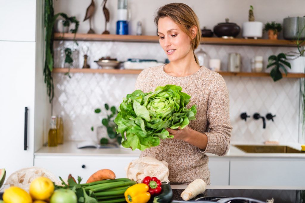 Frau steht in moderner Küche mit Salat in Hand bei Produkt Foto Shooting München