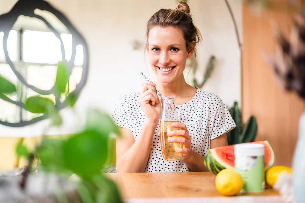 Frau lacht mit Flasche in Hand Sommer Melone Foto Shooting moderne Wohnung
