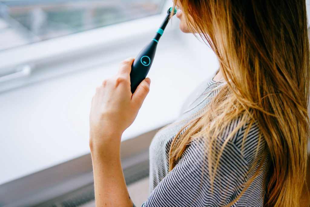Lifestyle Fotoshooting Happybrush Frau hält elektrische Zahnbürste vor Fenster