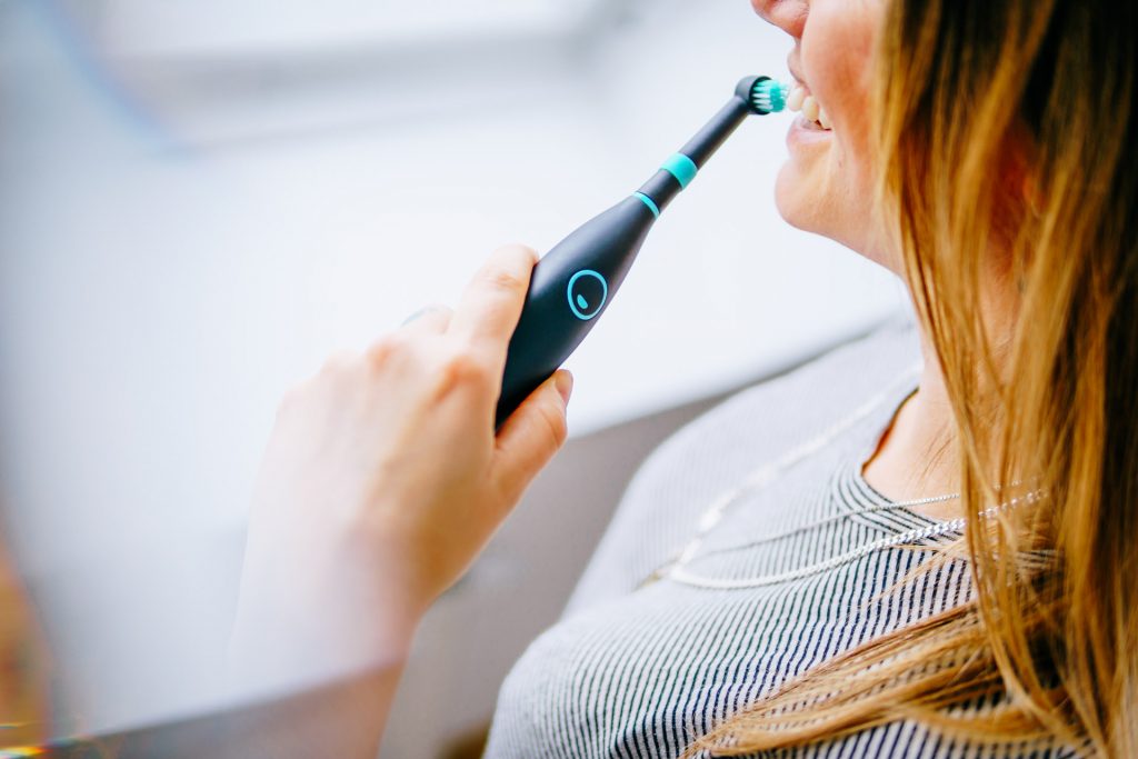 Lifestyle Fotoshooting Happybrush Frau hält elektrische Zahnbürste vor Fenster