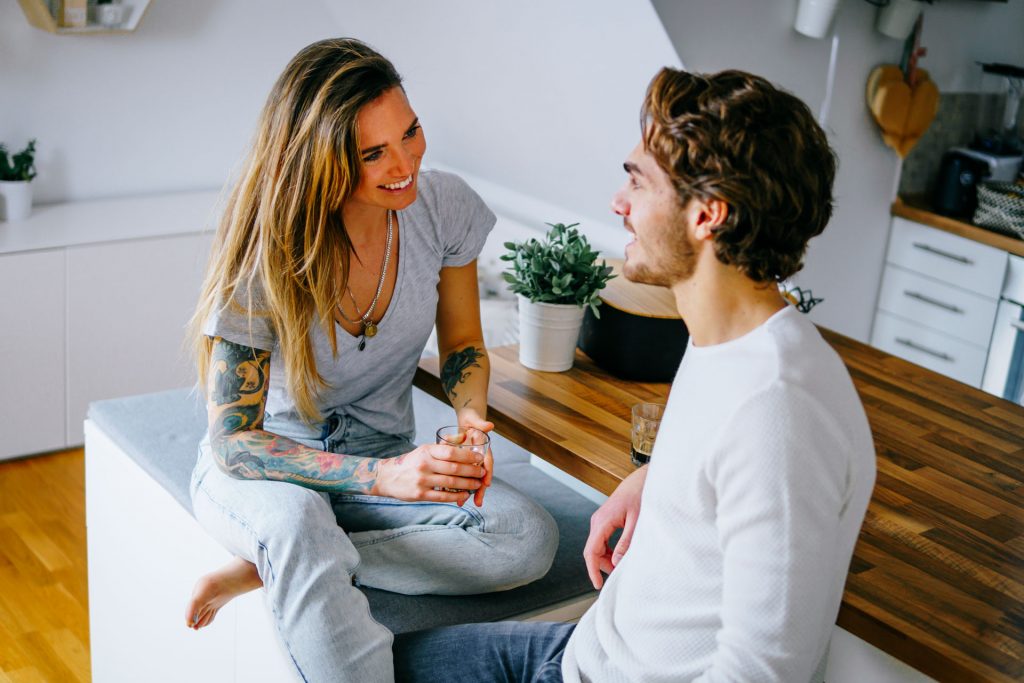 Paar sitzt in Wohnung und lacht bei Fotoshooting Lifestyle Happybrush