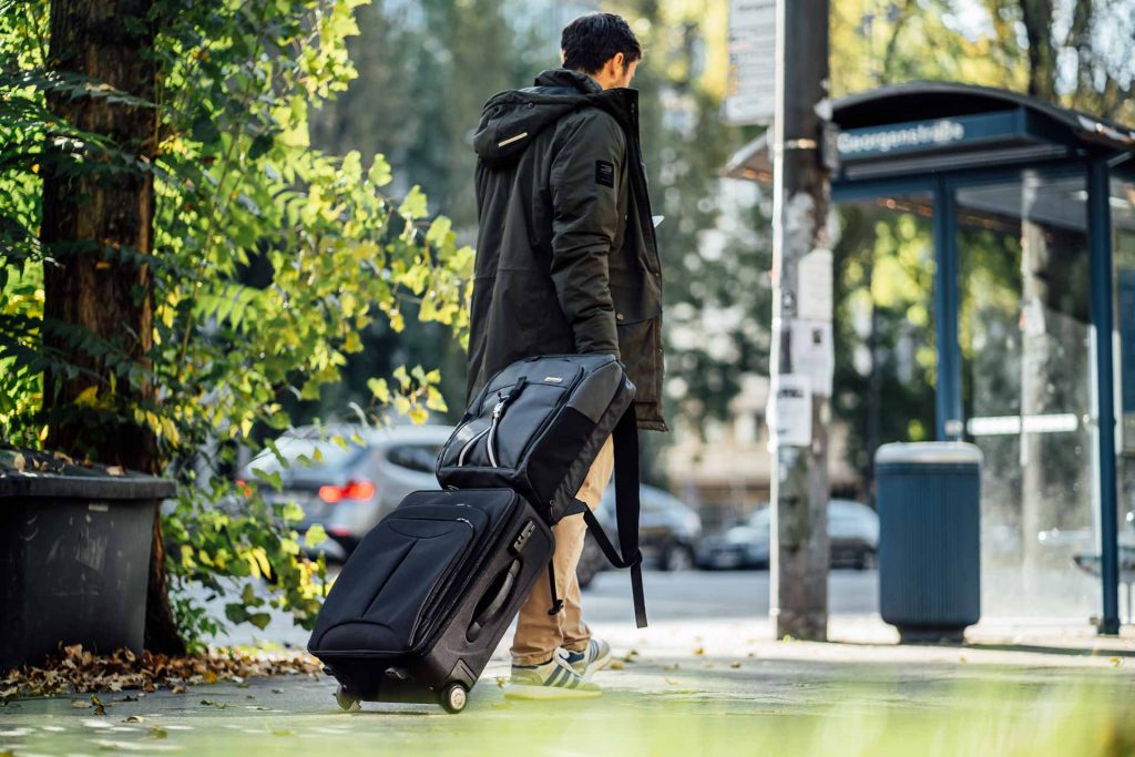 Fashion Lifestyle Shooting Jaimie Jacobs Mann mit Rucksack bei Bushaltestelle