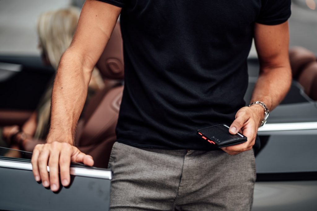 Produkt Fotoshooting München Geldbeutel Street Photography Startup Mann hält Geldbeutel in Hand vor Auto